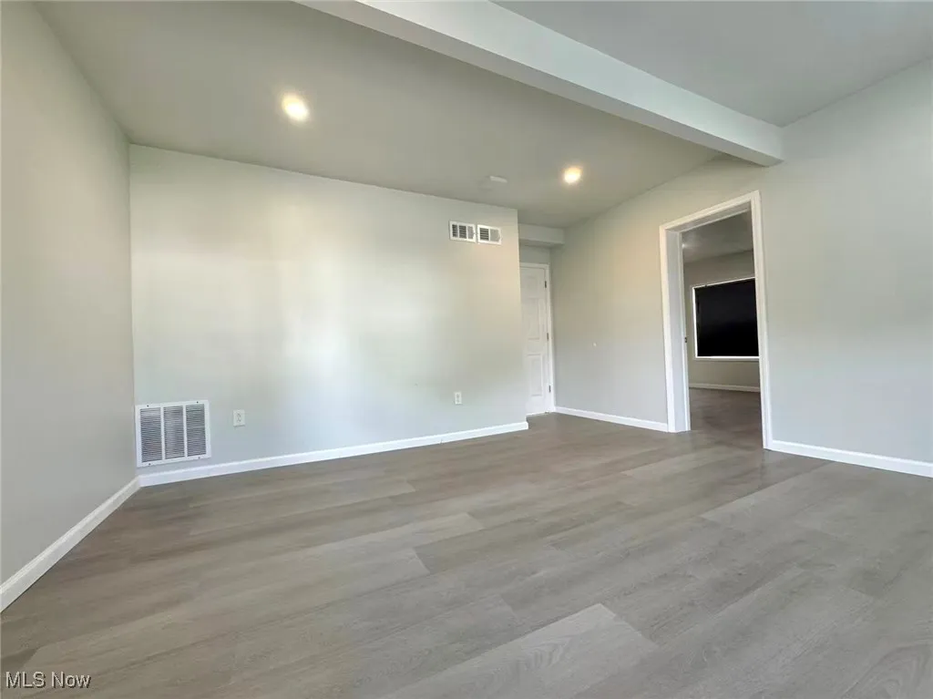 Spare room featuring light wood-style flooring, recessed lighting, and beam ceiling