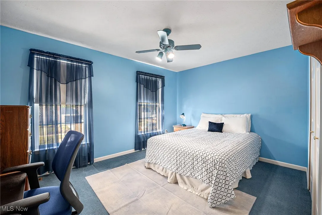 Carpeted bedroom with a ceiling fan and baseboards