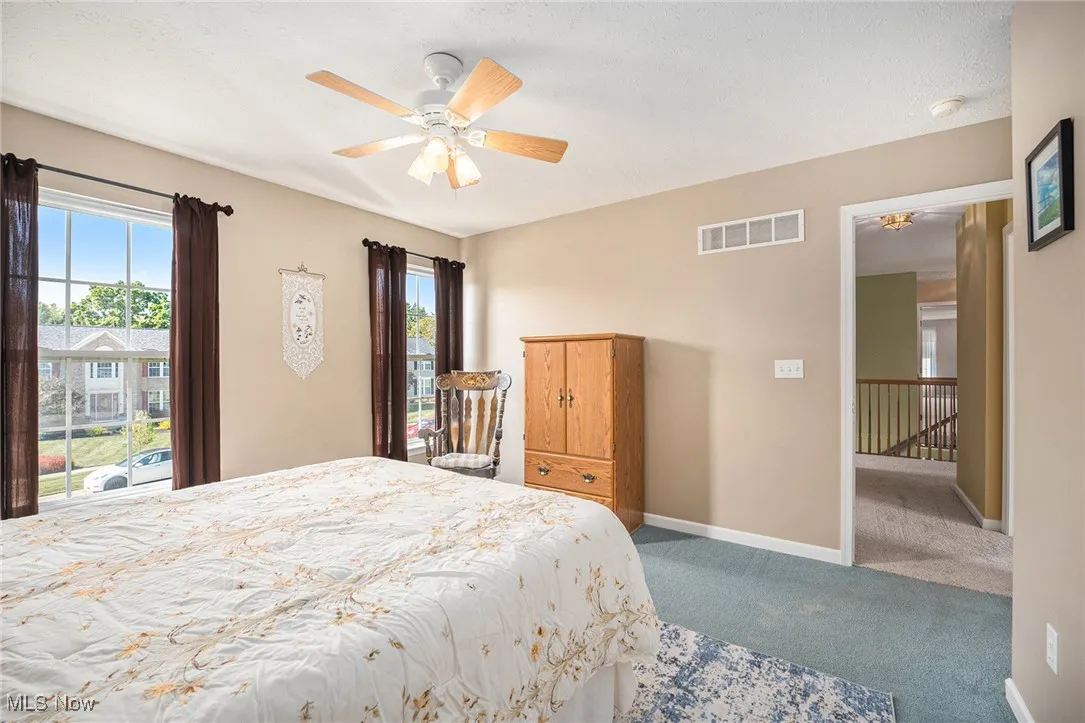 Bedroom featuring carpet flooring, multiple windows, a ceiling fan, and a textured ceiling