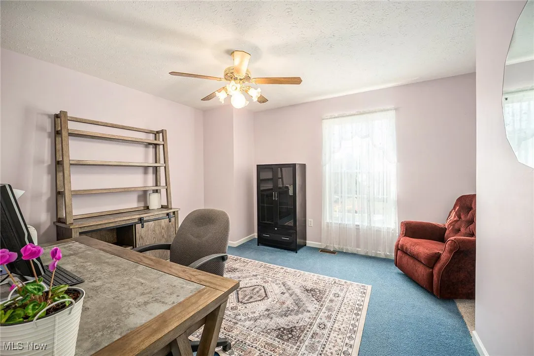 Home office with carpet floors, a textured ceiling, and ceiling fan