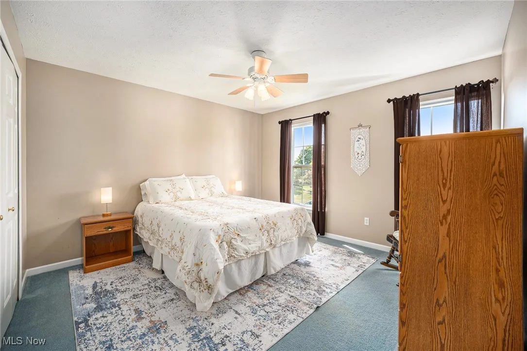 Carpeted bedroom featuring a textured ceiling, a closet, and ceiling fan