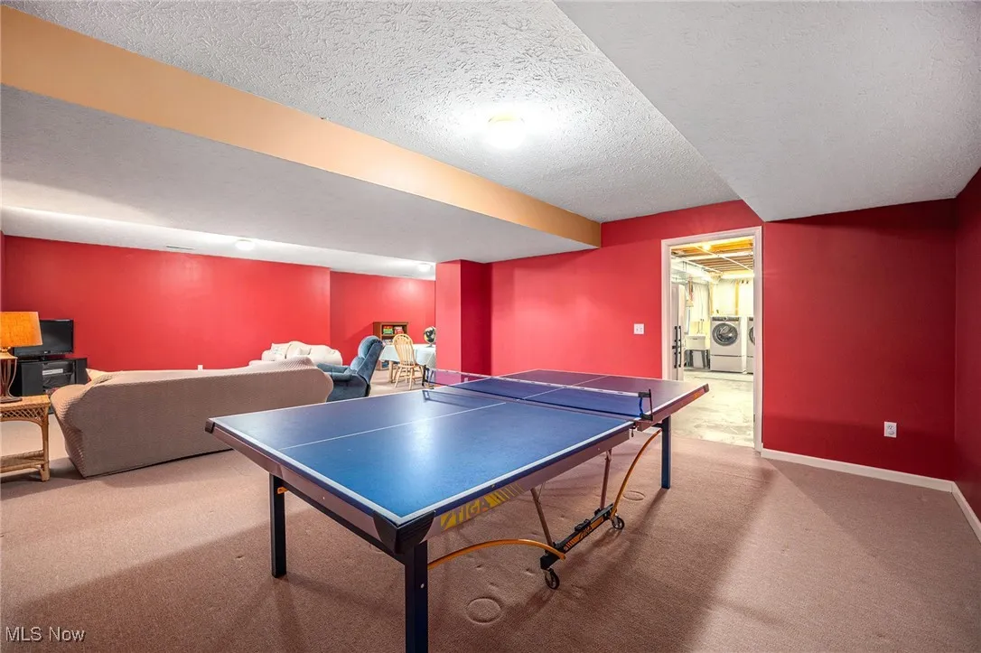 Playroom with carpet flooring, washing machine and dryer, and a textured ceiling