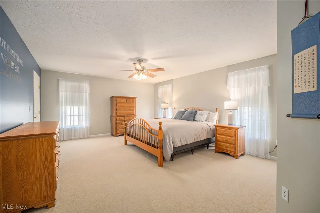 Bedroom with light carpet, a textured ceiling, and ceiling fan