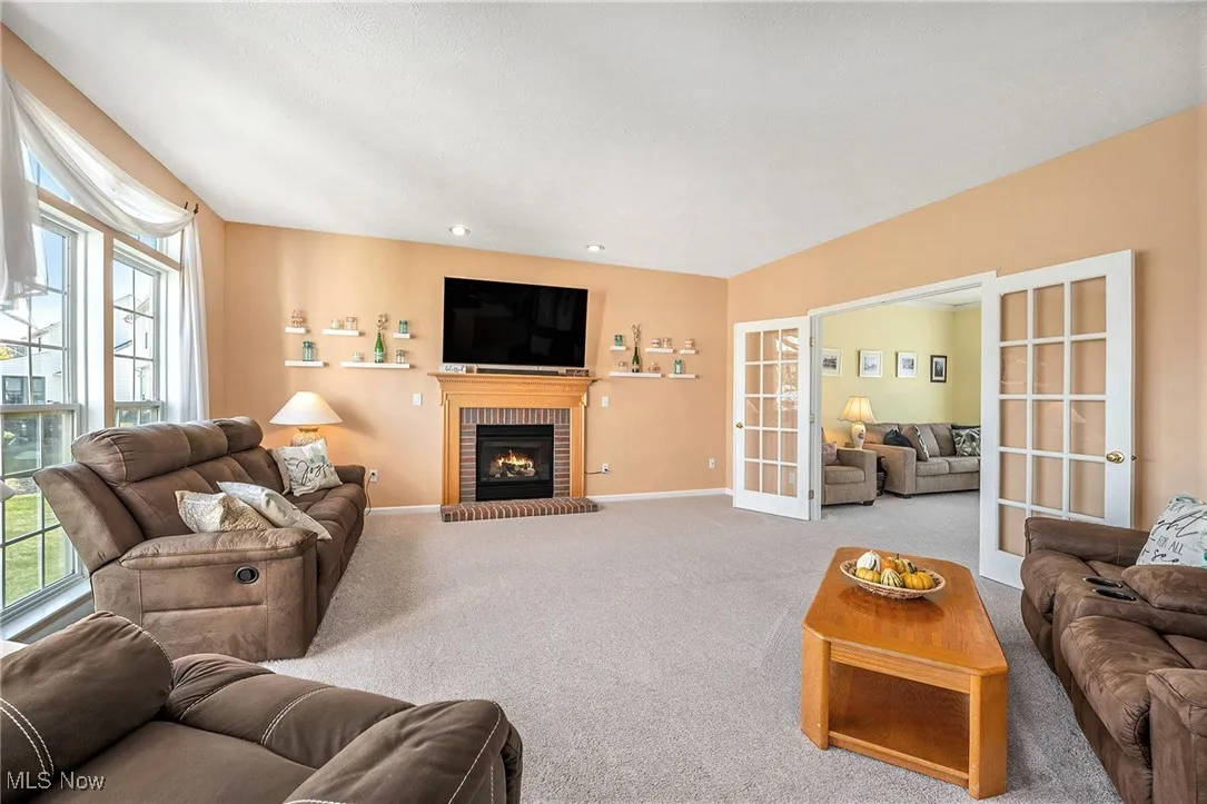 Carpeted living room with french doors and a brick fireplace