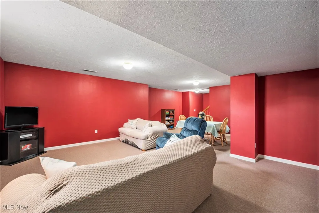 Carpeted living area featuring baseboards and a textured ceiling
