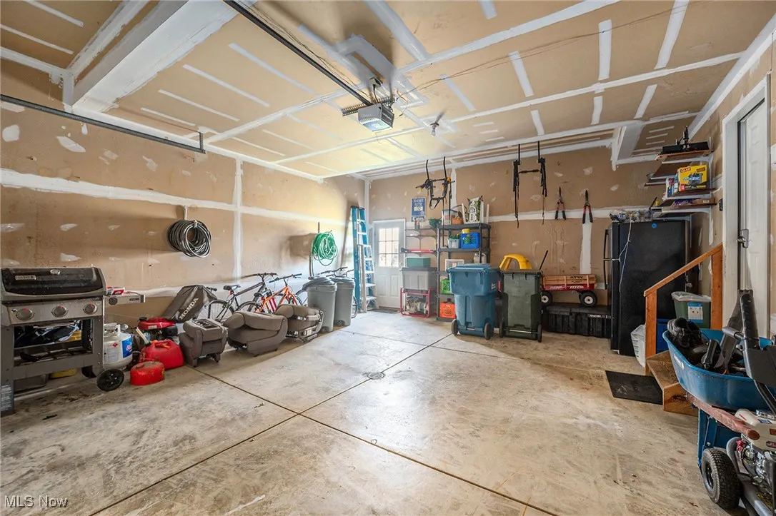Garage featuring freestanding refrigerator and a garage door opener