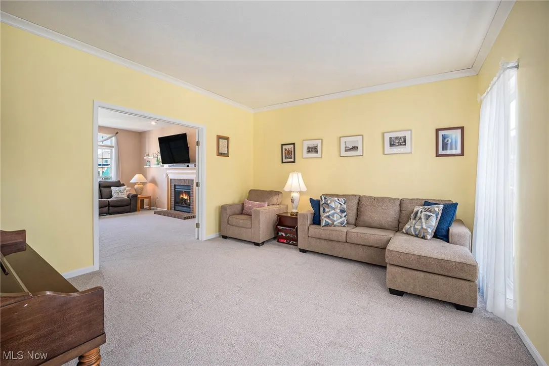 Carpeted living area with crown molding and a brick fireplace