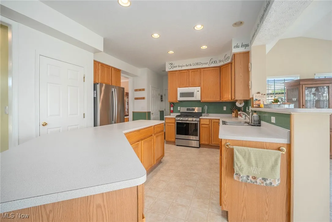 Kitchen featuring light countertops, stainless steel appliances, recessed lighting, a peninsula, and backsplash