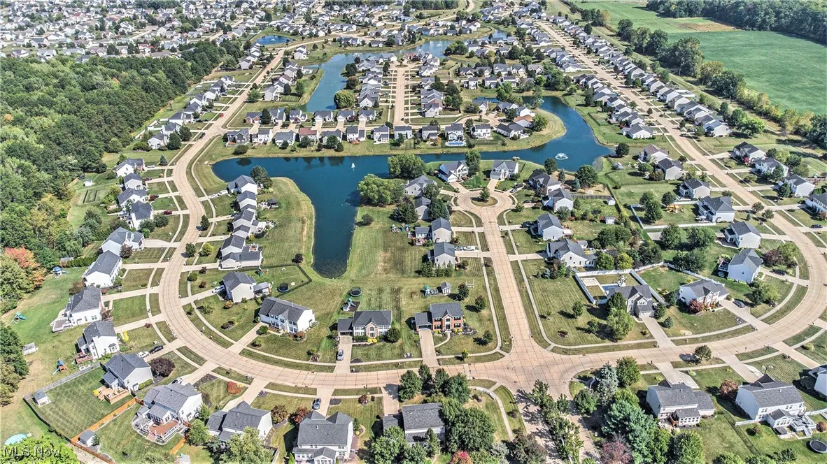Aerial view of property and surrounding area featuring nearby suburban area and a large body of water