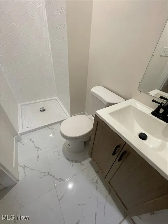 Bathroom with vanity, a shower stall, and light marble finish flooring