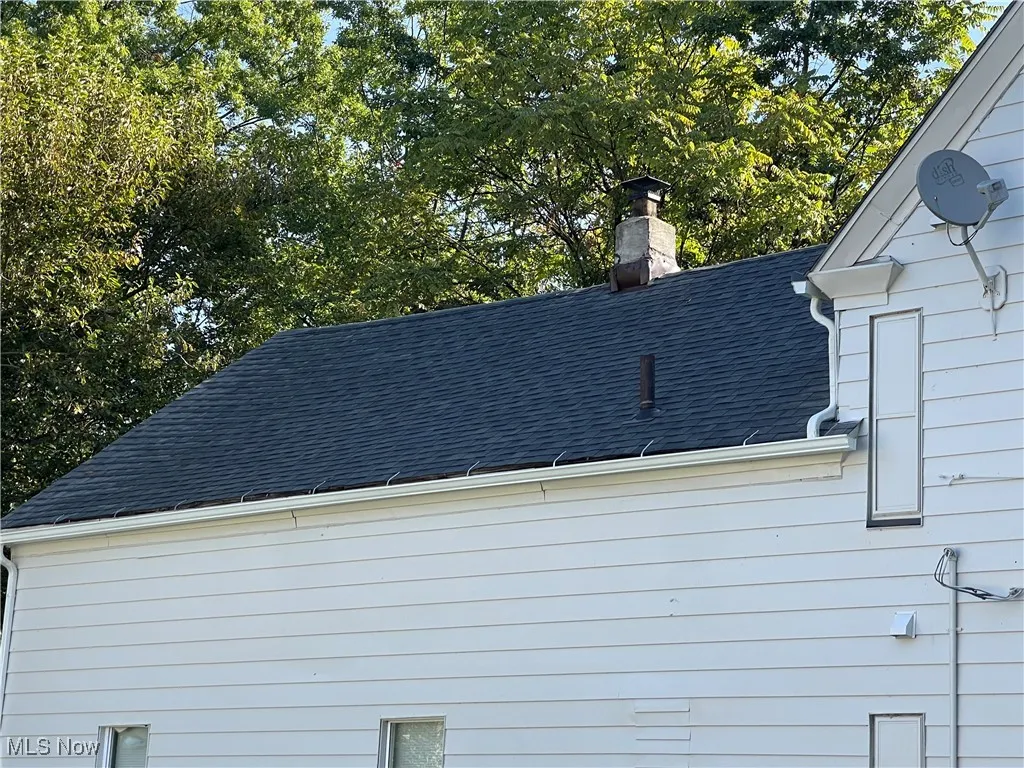 Exterior view of gutters, roof with shingles, a downspout, and a chimney
