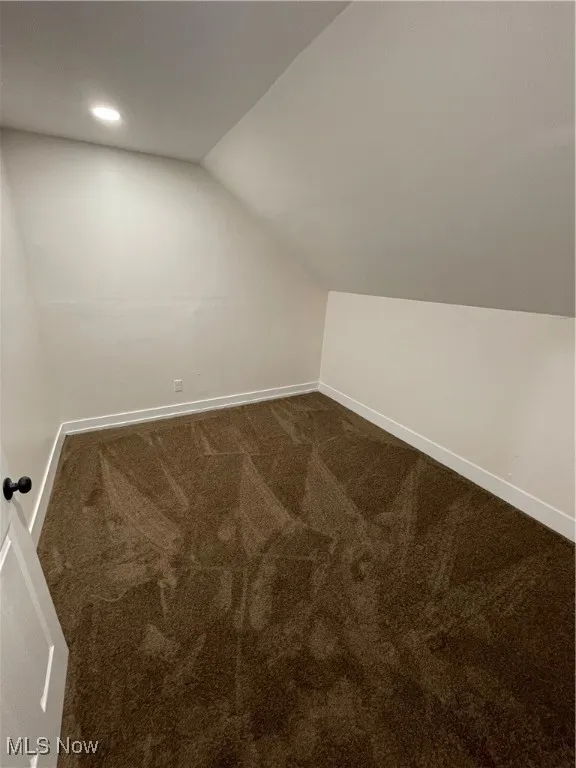 Additional living space featuring dark colored carpet, lofted ceiling, and recessed lighting