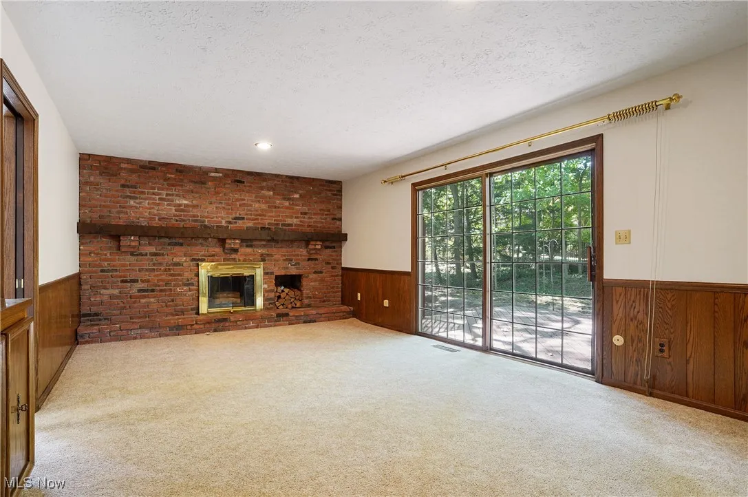 Family room with wall of brick and fireplace and slider to deck and backyard.