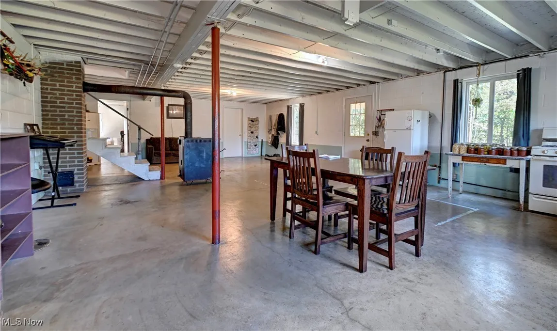 Dining room featuring concrete flooring, healthy amount of natural light, stairway, and a baseboard radiator