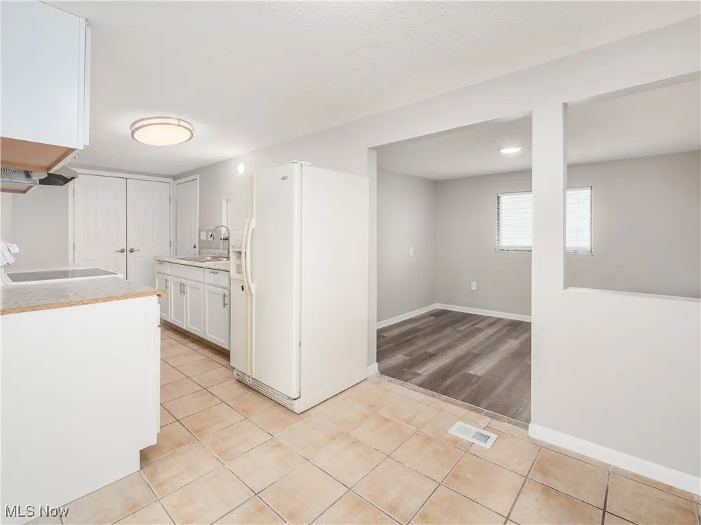 Kitchen featuring light countertops, white cabinetry, light tile patterned flooring, white refrigerator with ice dispenser, and stove