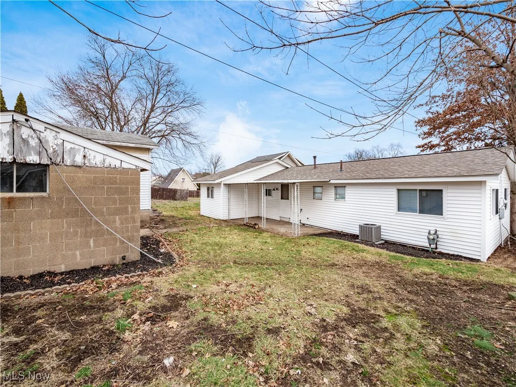 Back of property featuring a patio, a shingled roof, and a yard
