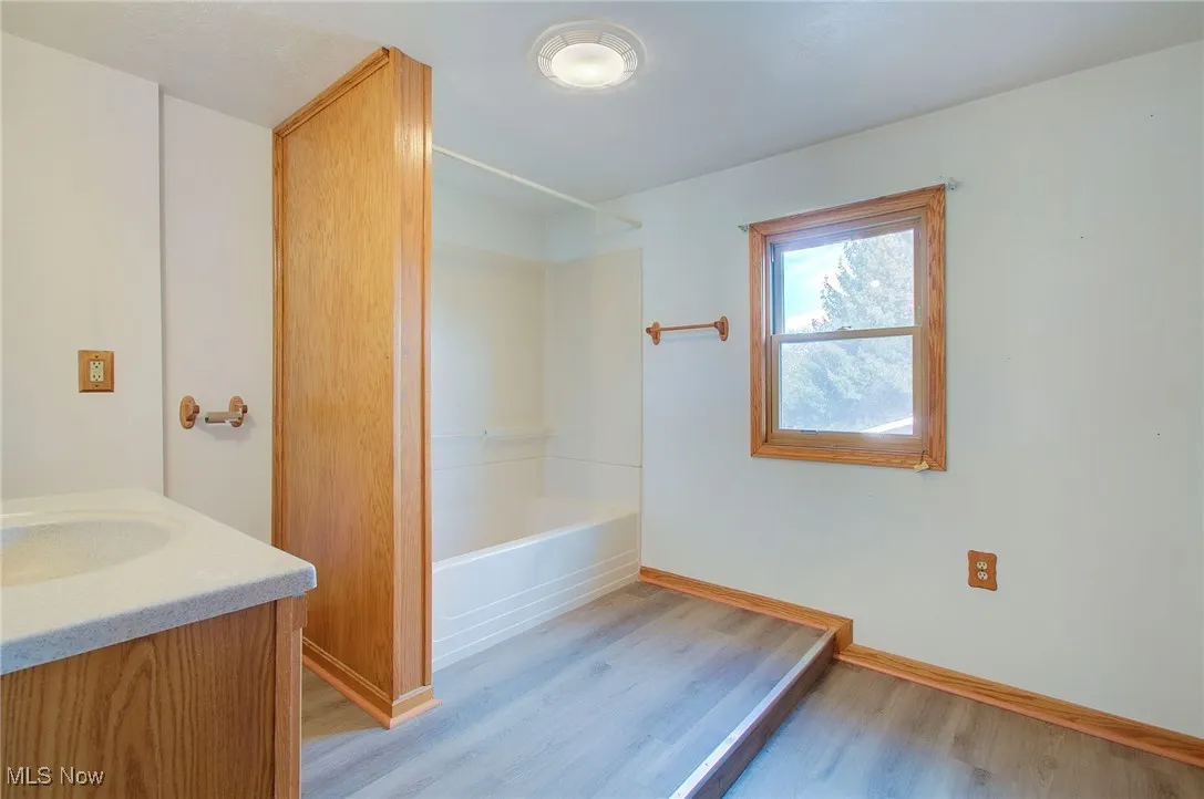 Bathroom with light wood finished floors, vanity, and shower / washtub combination