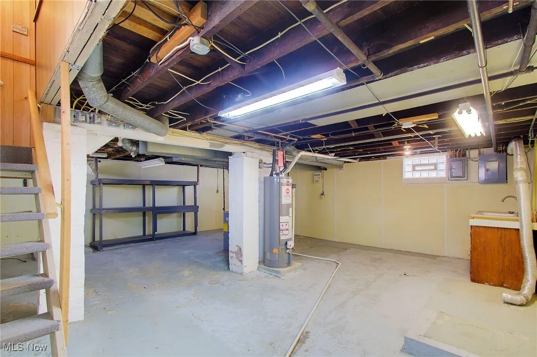 Basement with stairway, electric panel, and water heater