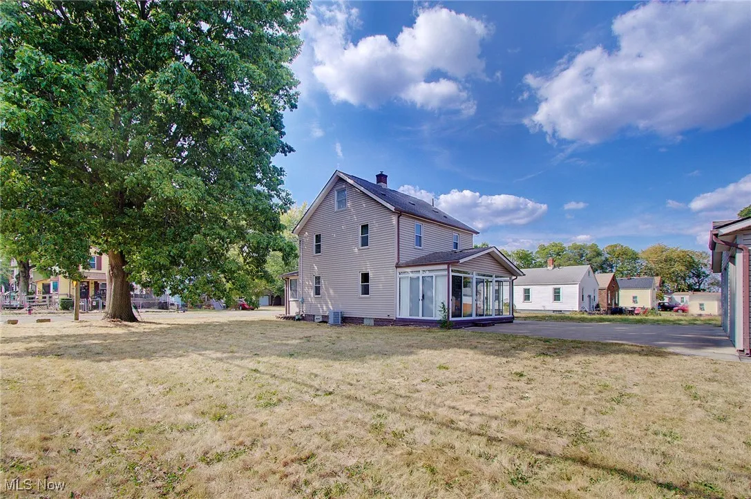 Back of house featuring a sunroom, a lawn, and a chimney