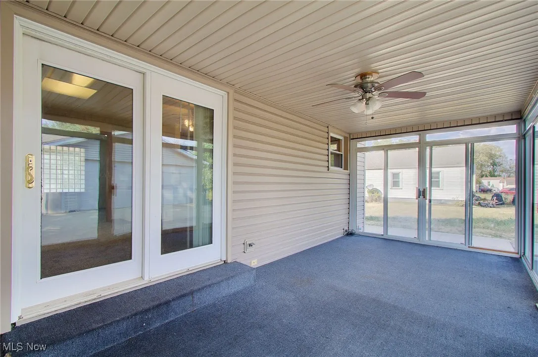 Unfurnished sunroom with a ceiling fan and french doors