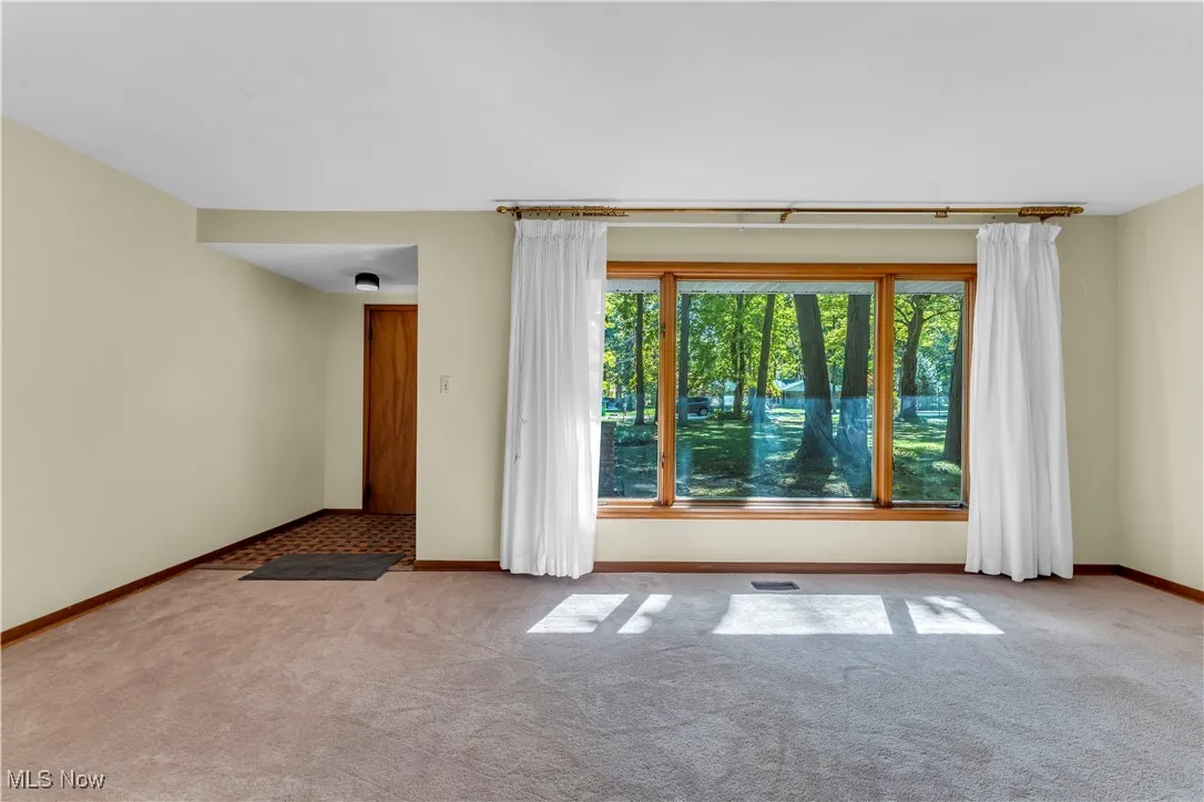 Spare room featuring carpet flooring and baseboards
