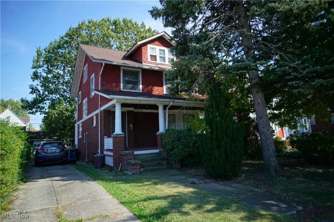 American foursquare style home with a porch, concrete driveway, and a front lawn