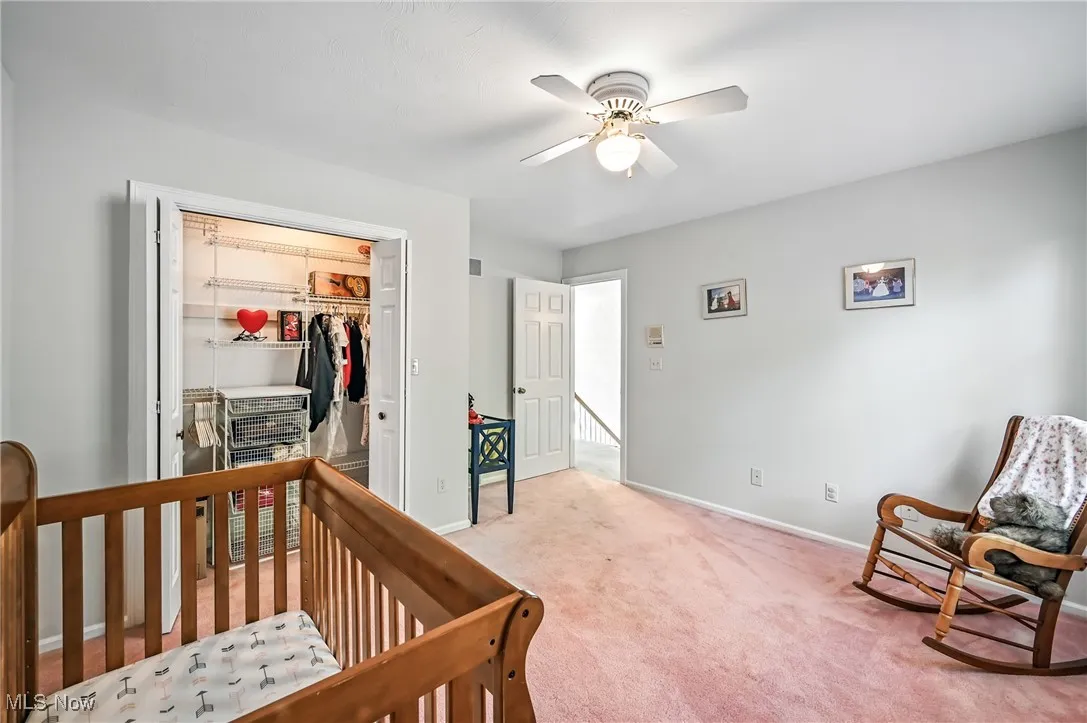 Carpeted bedroom featuring baseboards and a ceiling fan, custom closet