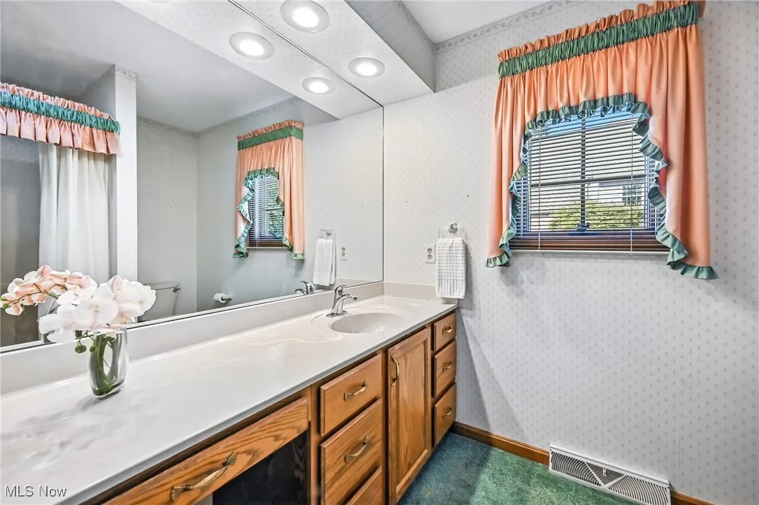 Bathroom featuring wallpapered walls, vanity, and recessed lighted vanity, linen closet , tub/shower