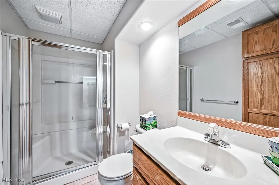 Full bath featuring a drop ceiling, vanity, a stall shower, and ceramic tile