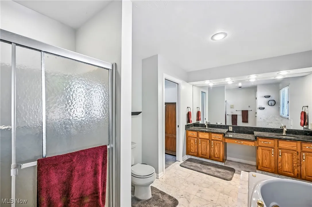 Full bathroom featuring a stall shower, double vanity, and light marble finish floors