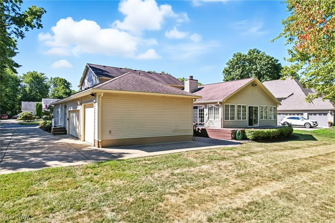 Back of house featuring driveway, a lawn, and an attached garage