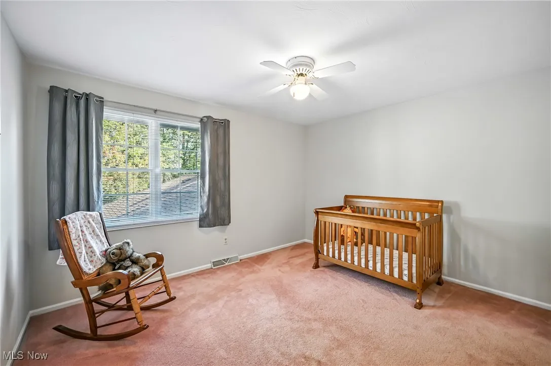 Bedroom with a nursery area, carpet, and ceiling fan