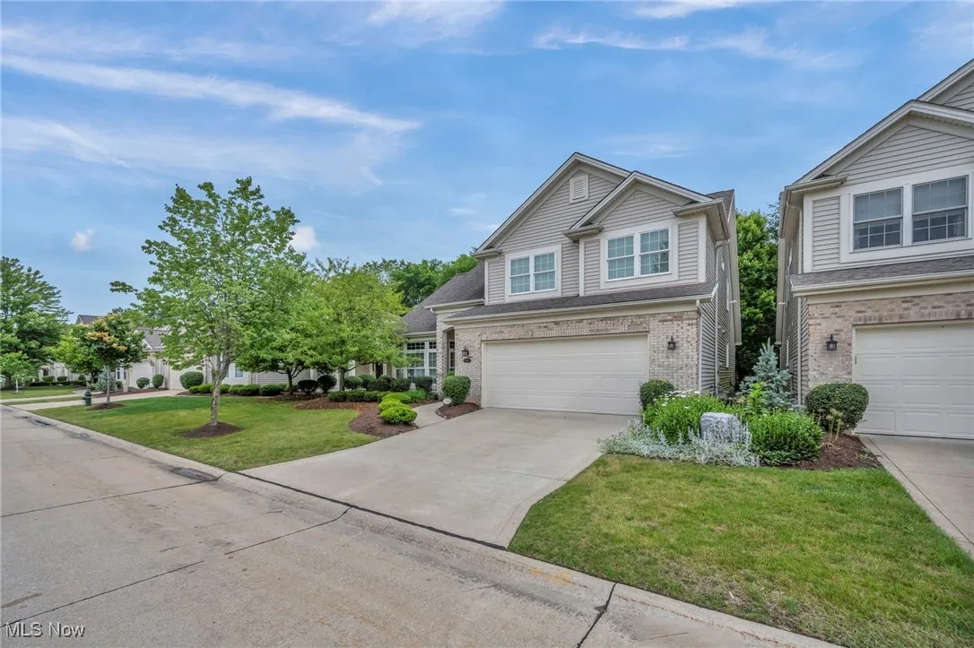 Traditional-style home featuring a front lawn, concrete driveway, brick siding, and a garage