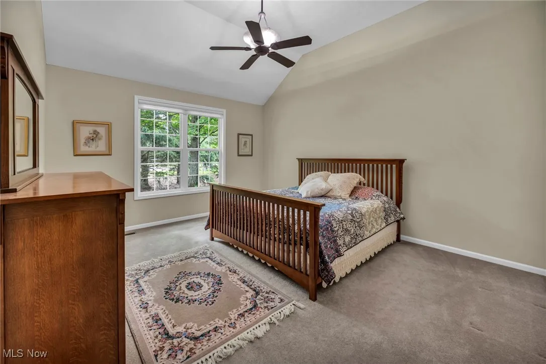 Carpeted bedroom featuring lofted ceiling and ceiling fan