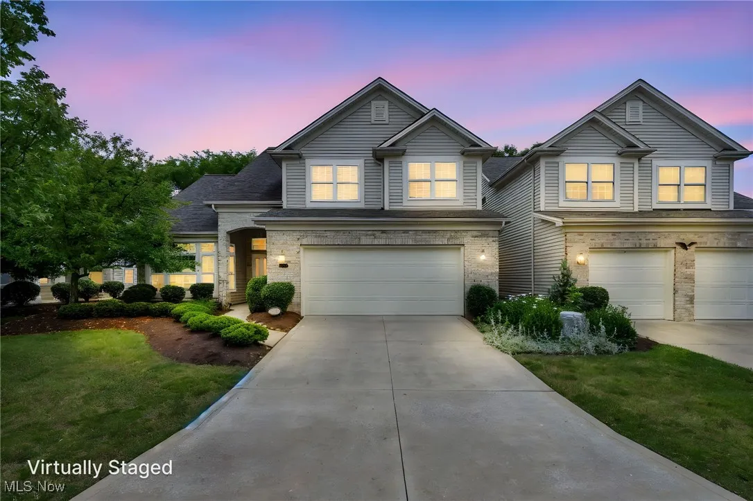 Traditional-style home with driveway, a garage, brick siding, and a front yard