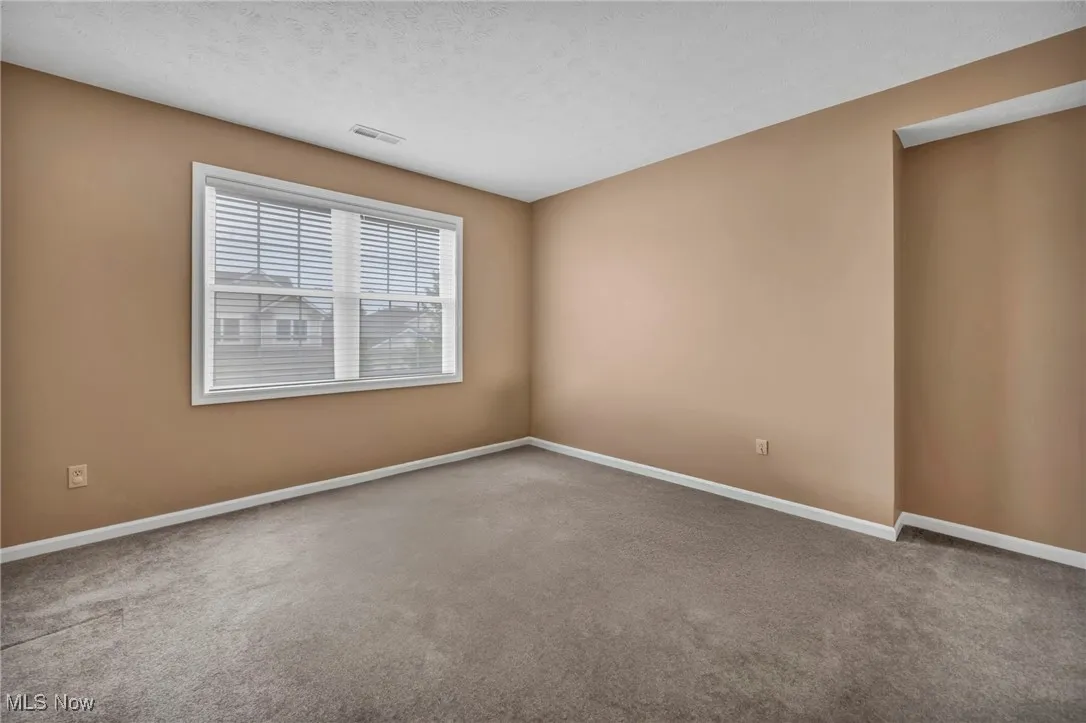 Unfurnished room with a textured ceiling and carpet flooring