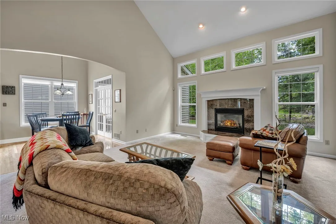 Living area featuring high vaulted ceiling, light carpet, arched walkways, recessed lighting, and a fireplace
