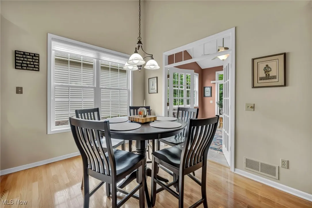 Dining space with light wood-style flooring, a chandelier, and a towering ceiling