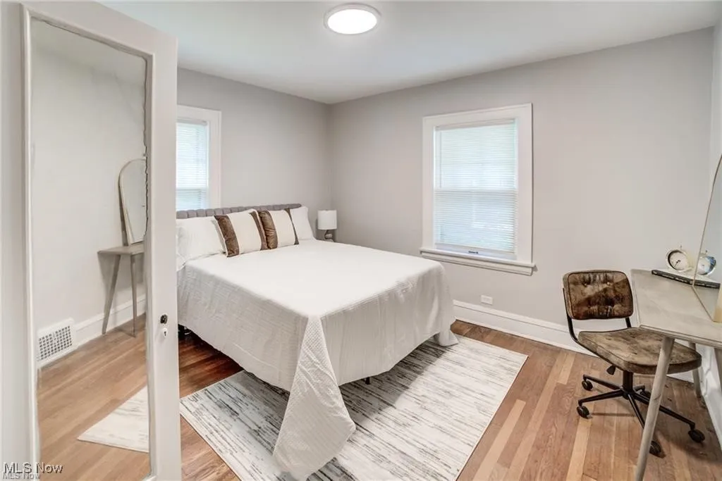 Bedroom featuring light wood-style floors, multiple windows, and an office area