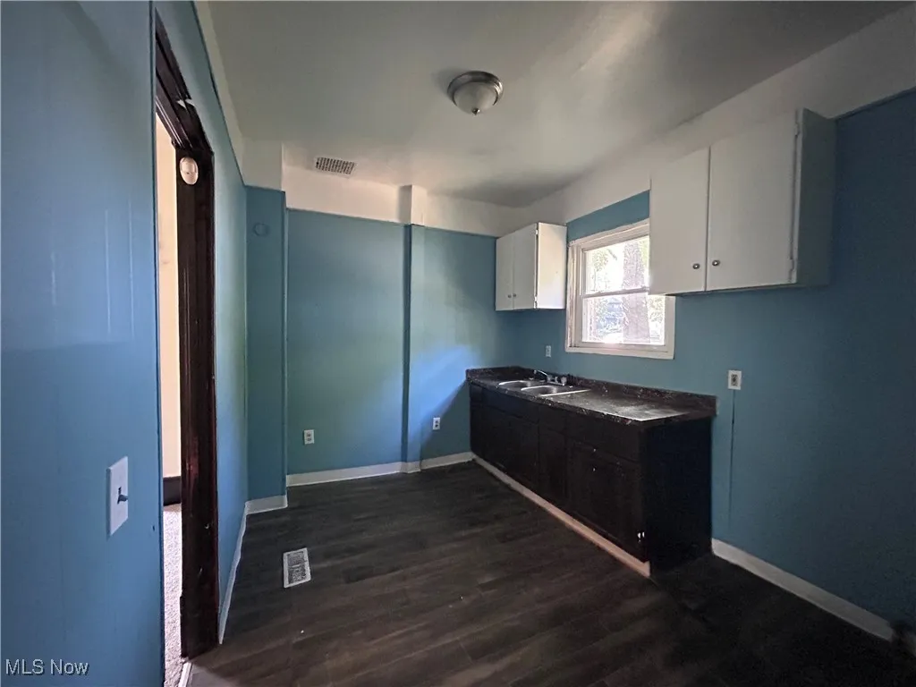 Kitchen with white cabinets, dark wood-type flooring, and dark countertops
