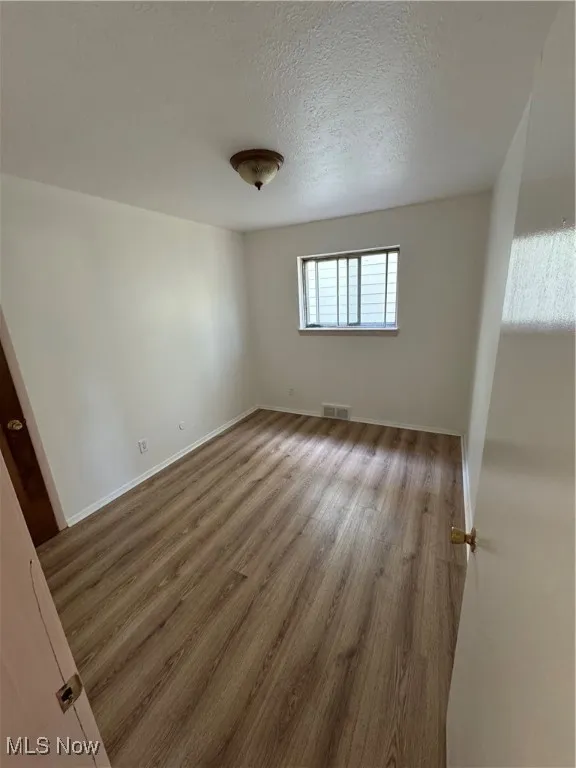 Unfurnished bedroom featuring wood finished floors and a textured ceiling