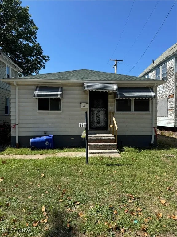 Bungalow-style home with roof with shingles and a front yard