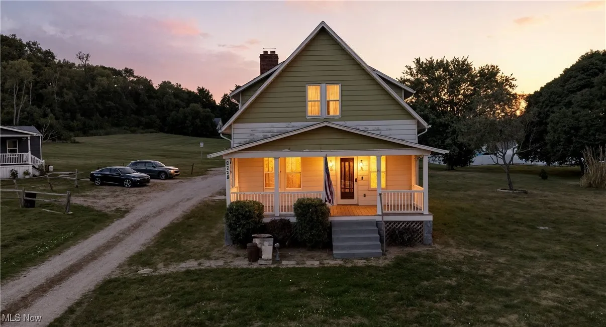 Back of property featuring covered porch, dirt driveway, a chimney, and a yard