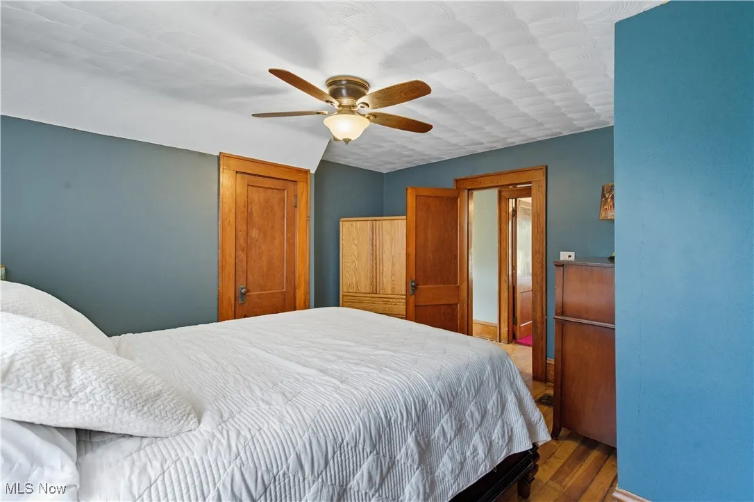 Bedroom with dark wood-style flooring and a ceiling fan
