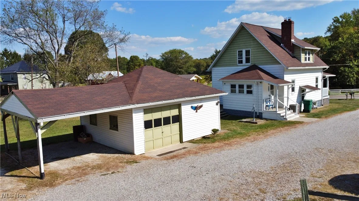 View of side of property featuring a shingled roof, a chimney, and driveway