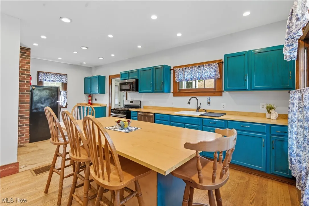 Kitchen featuring blue cabinets, light wood-type flooring, plenty of natural light, stainless steel appliances, and recessed lighting