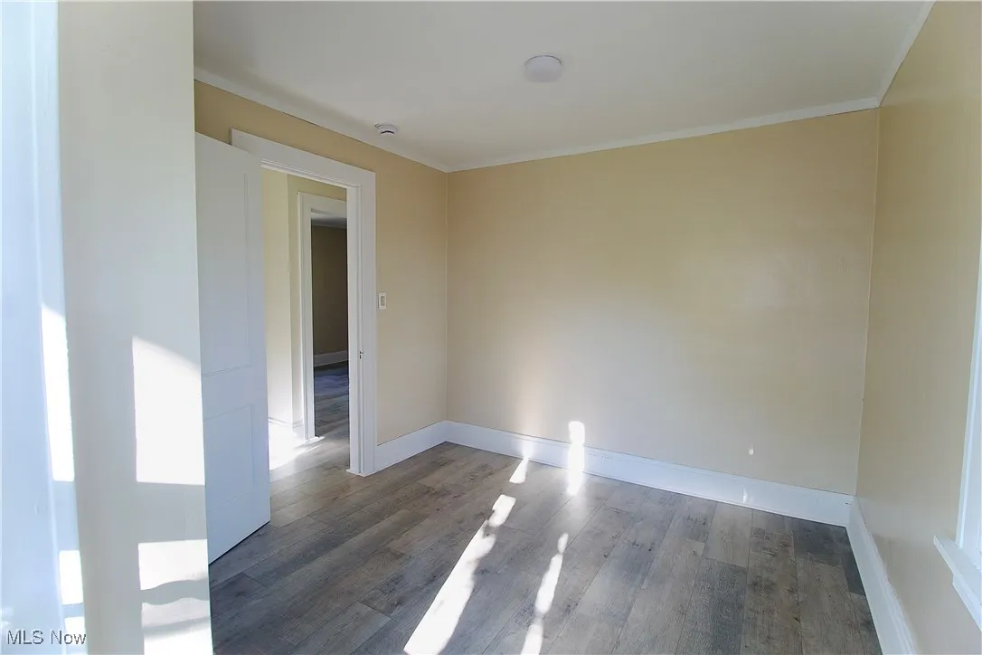 Empty room with wood finished floors and crown molding