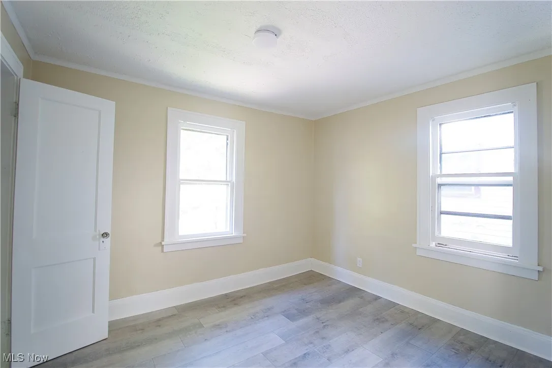 Unfurnished room with light wood-style floors and ornamental molding