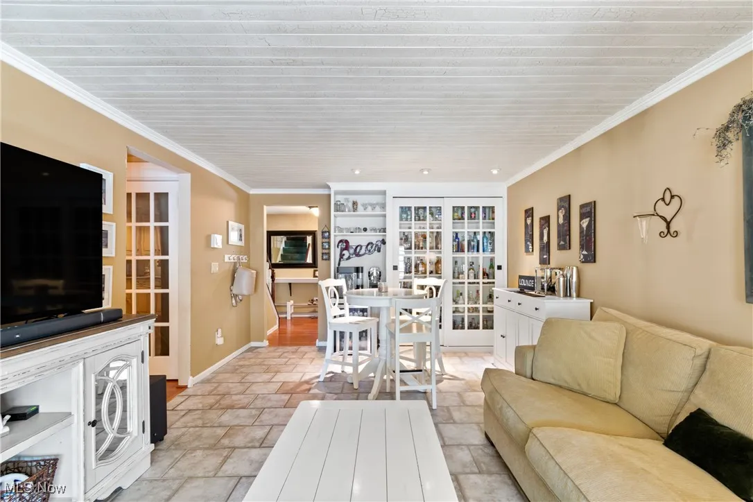 Living area featuring crown molding and light stone finish flooring