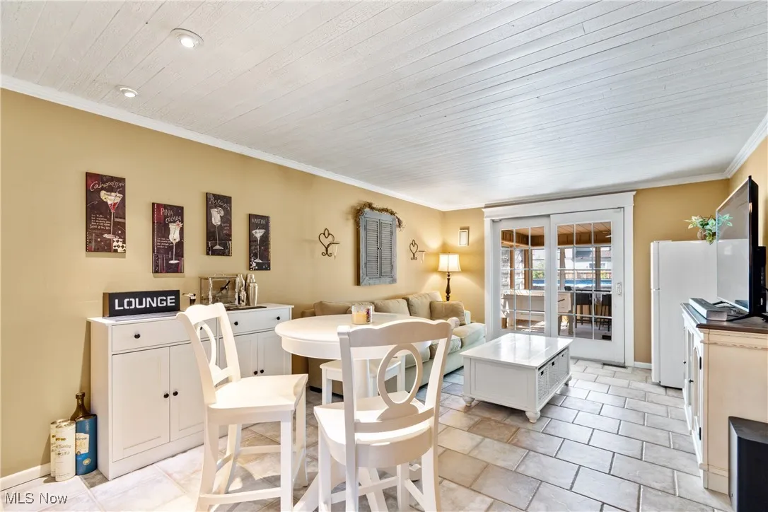 Dining room featuring ornamental molding, light tile patterned flooring, and wood ceiling